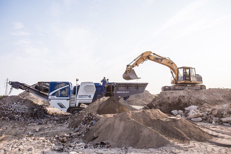 Machacadora móvil Kleemann Mobicat MC 110 R EVO triturando escombros de demolición alimentada por una excavadora CAT